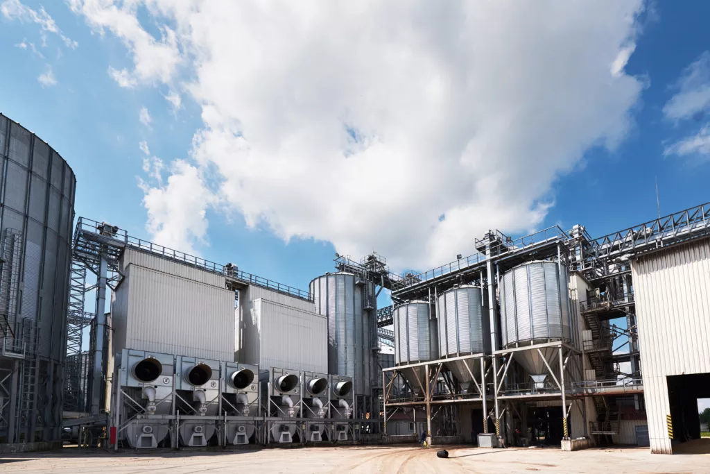 Agricultural Silos. Building Exterior. Storage and drying of grains, wheat, corn, soy, sunflower against the blue sky with white clouds